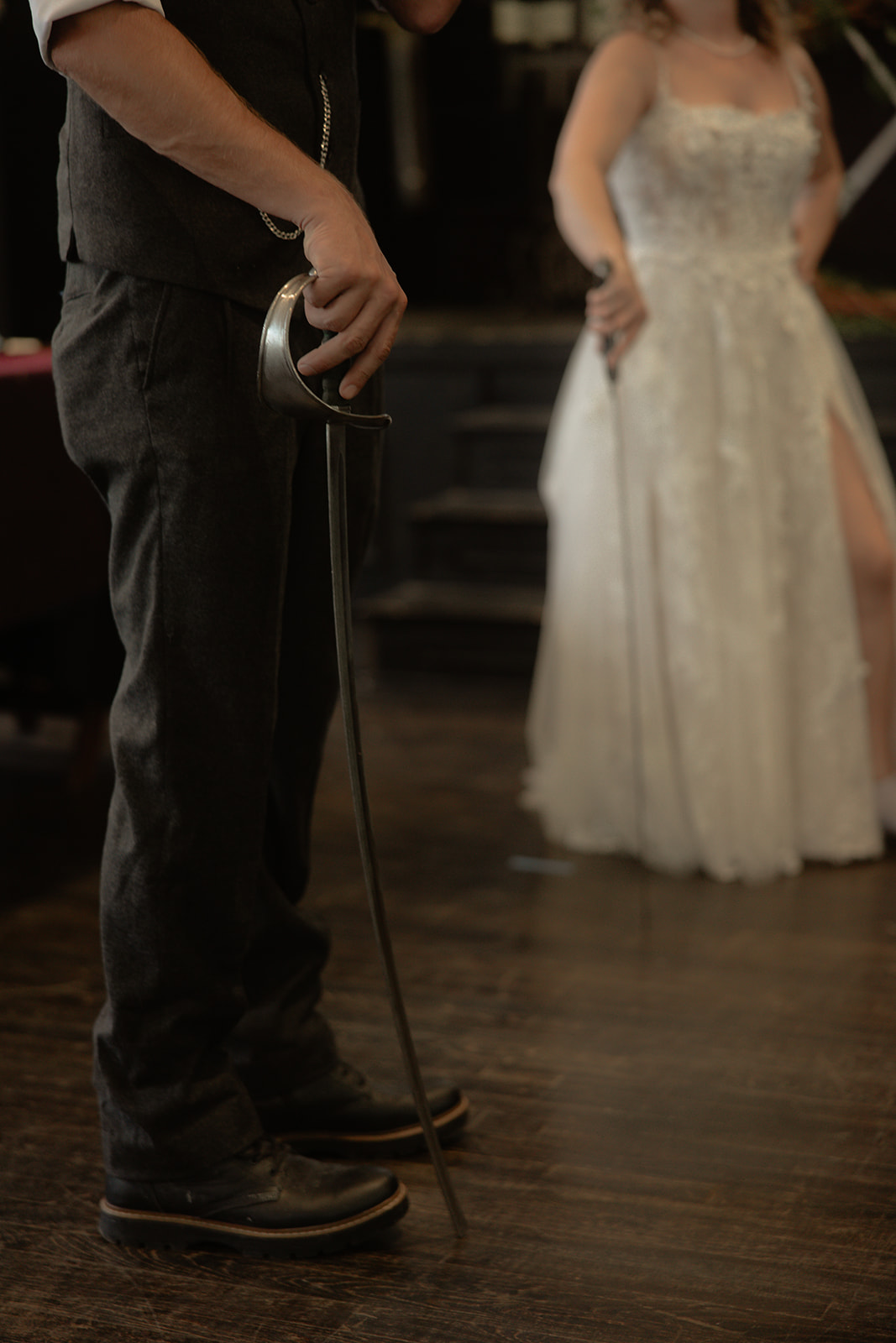A sword held at Matt's side with Dani in the background