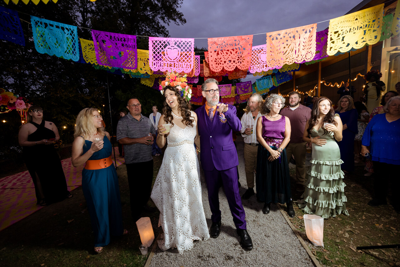 Benjamin and Alison with guests beneath colorful papel picado banners