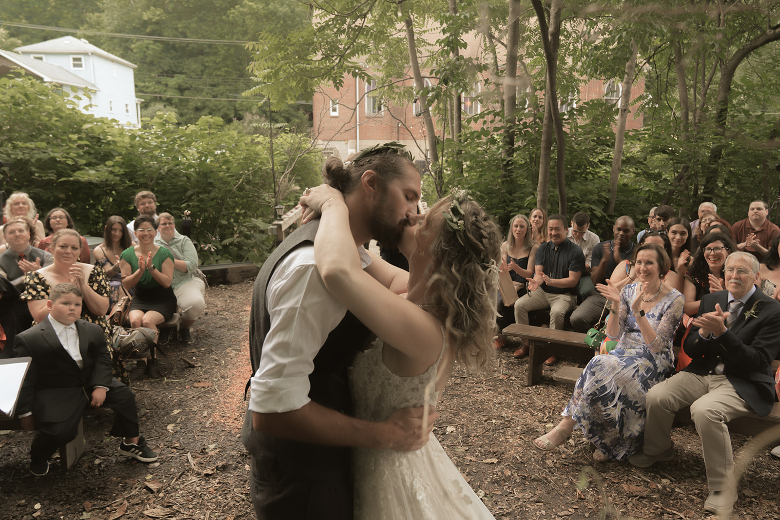 Dani and Matt kissing at the end of their outdoor ceremony while guests applaud