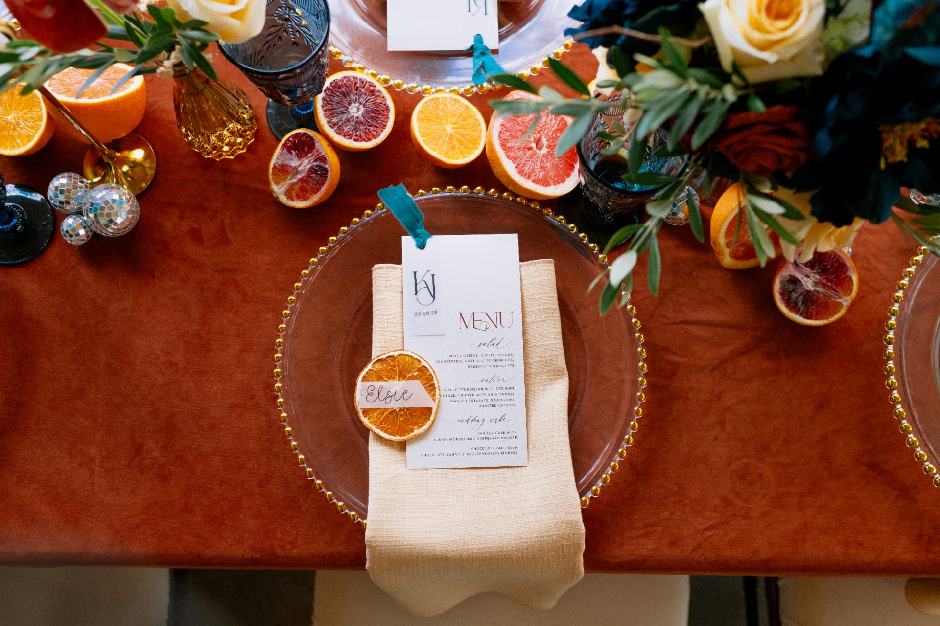 An overhead place setting with a menu, dried orange slice, and citrus