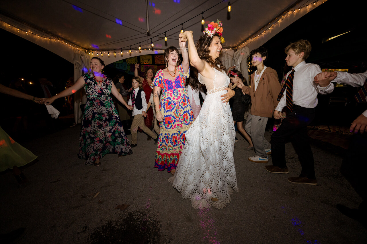 Alison in a flower crown dancing with guests under string lights at Tree Pittsburgh