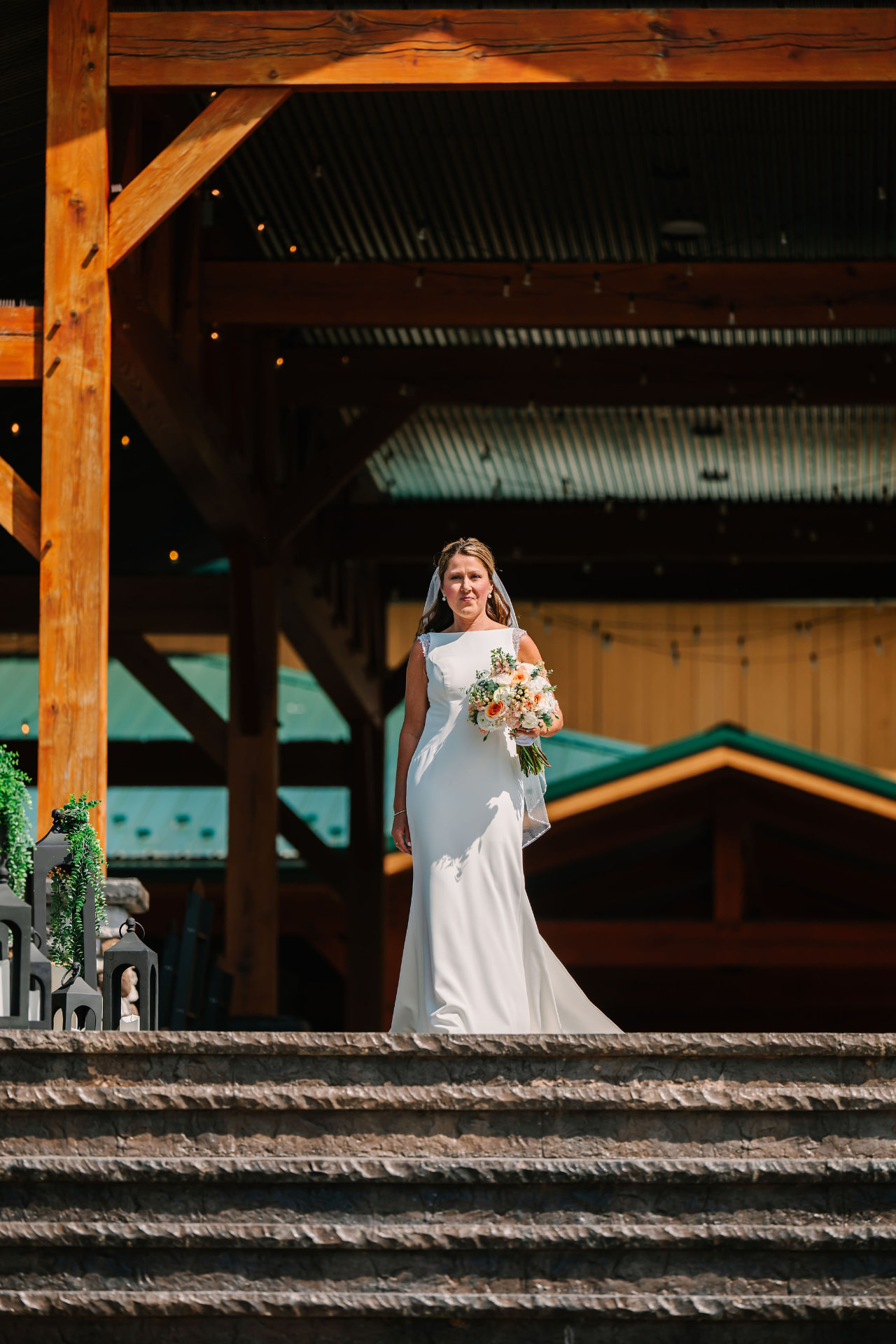 Sonnie holding her bouquet at the top of the steps under the timber pavilion