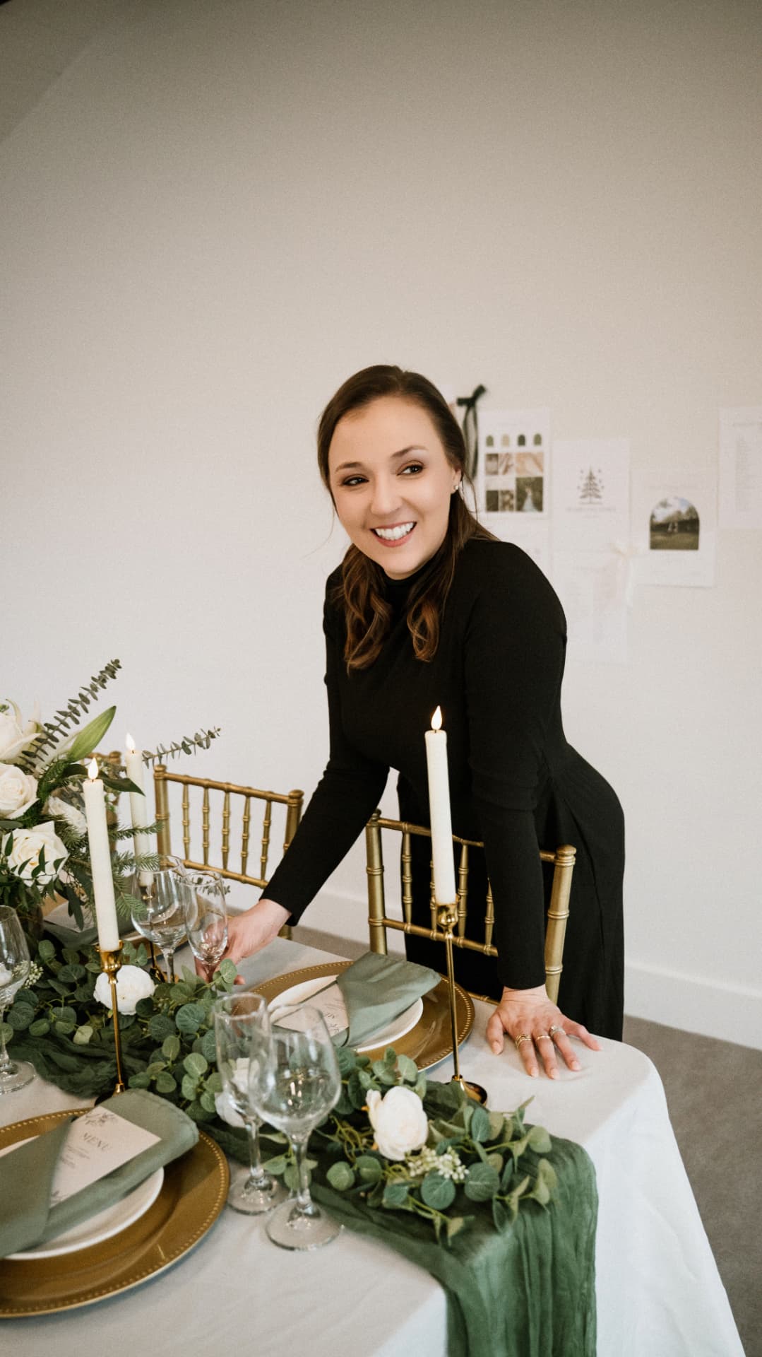 Tara smiling while setting a candlelit table with greenery