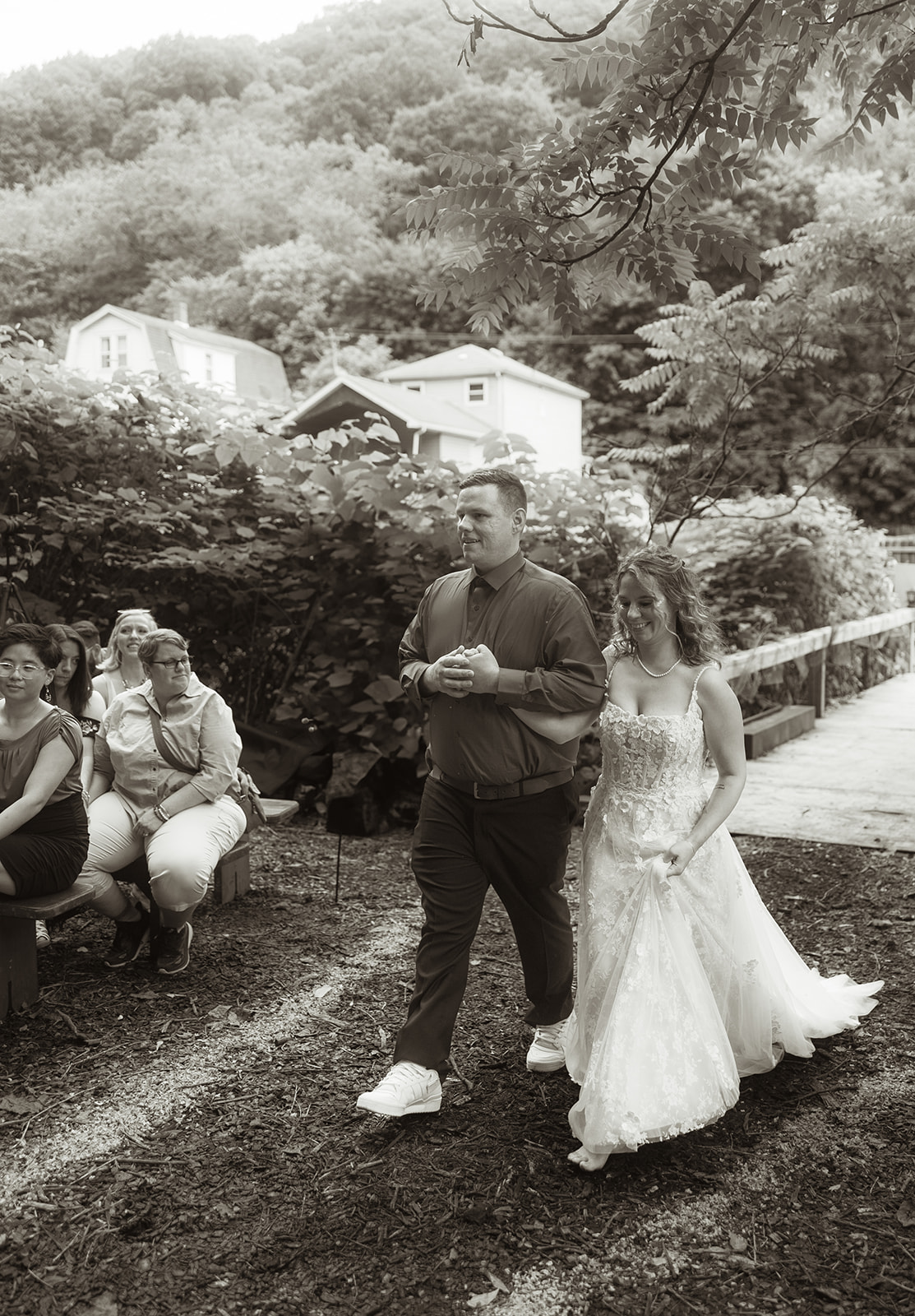 Dani walking down a wooded path past seated guests