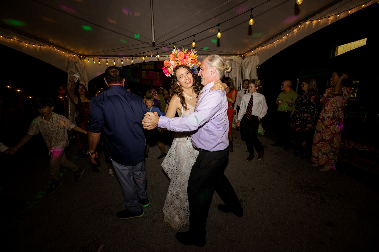 Alison dancing with a guest under string lights at the reception