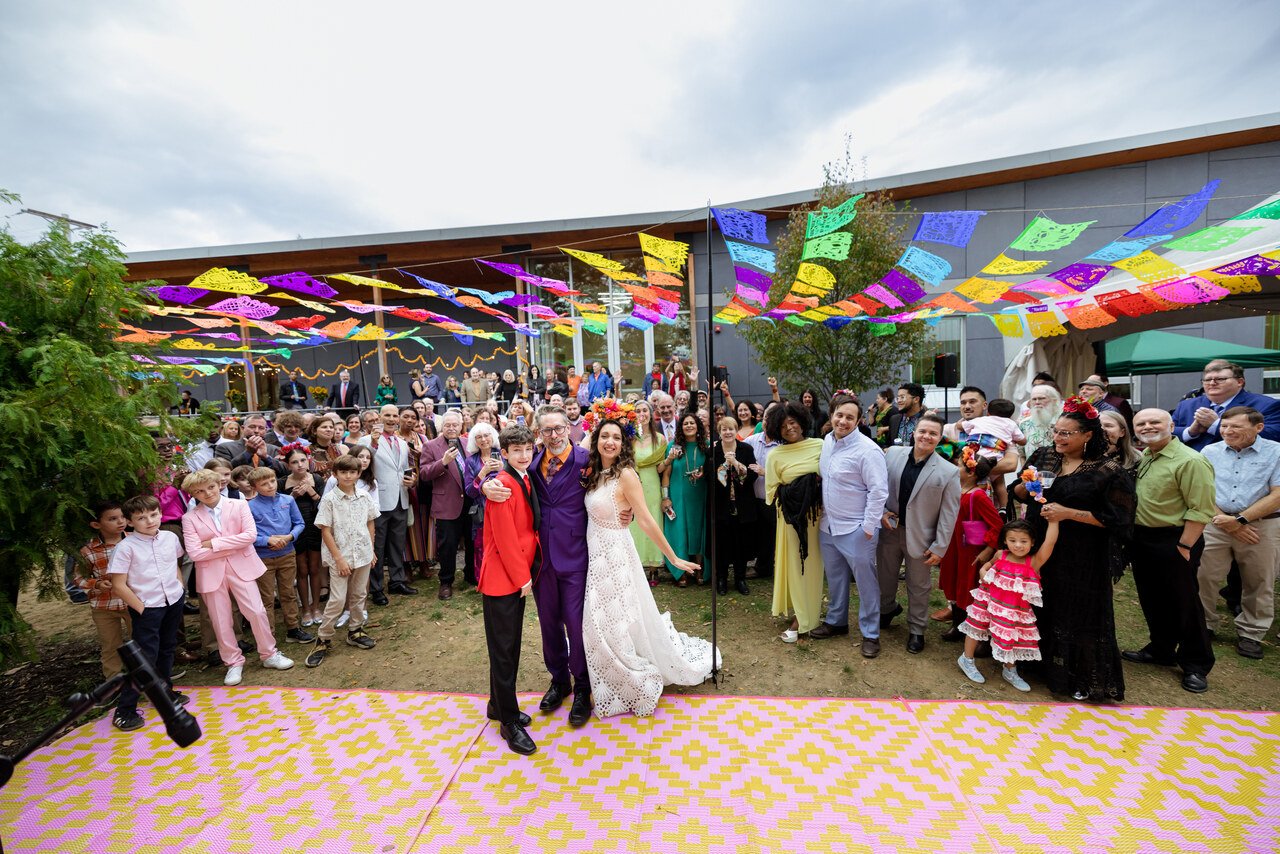 Benjamin and Alison surrounded by guests on the dance floor under papel picado